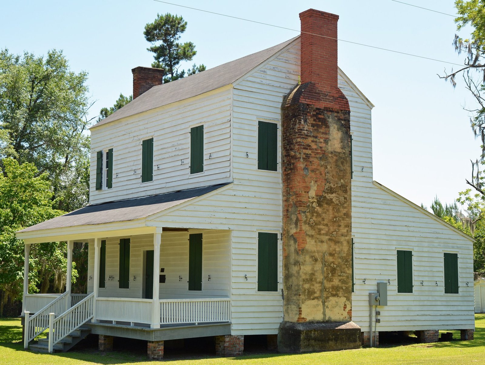 The white two-story Dell-Goodall House with green shutters and a large brick chimney