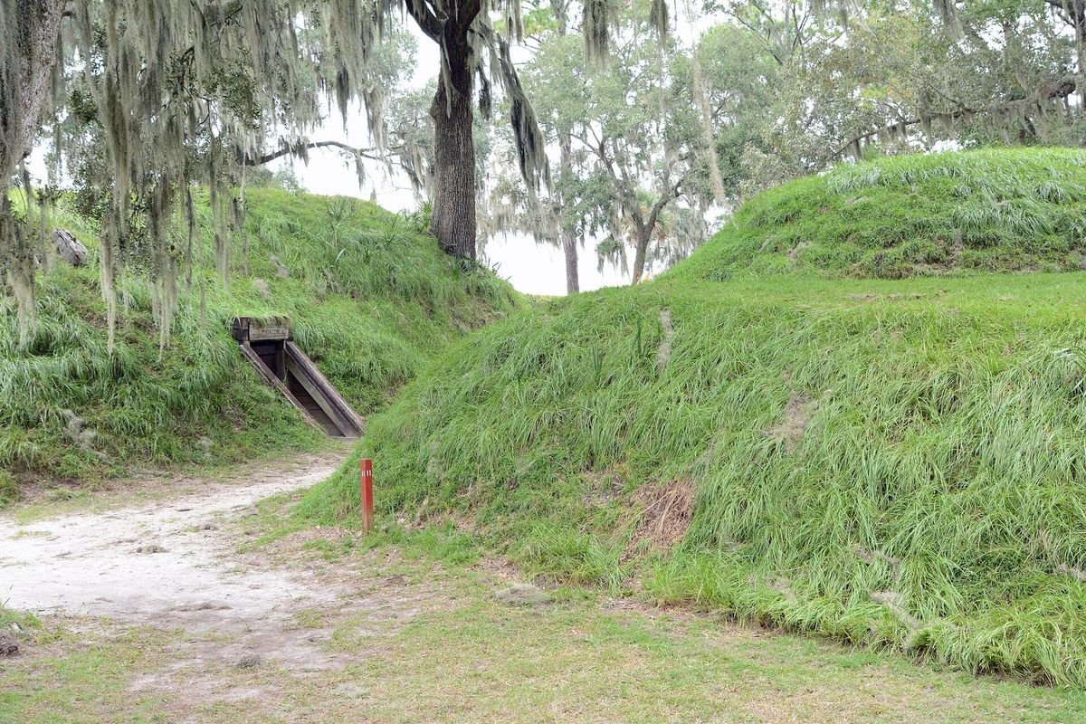 Grass-covered Confederate earthwork fortifications under Spanish moss at Fort McAllister Historic State Park