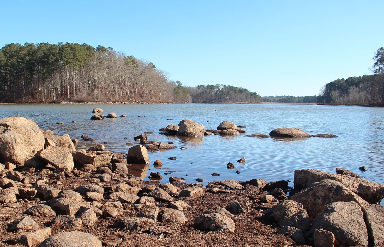 Granite boulders along the shore of the lake at Fort Yargo State Park on a clear day