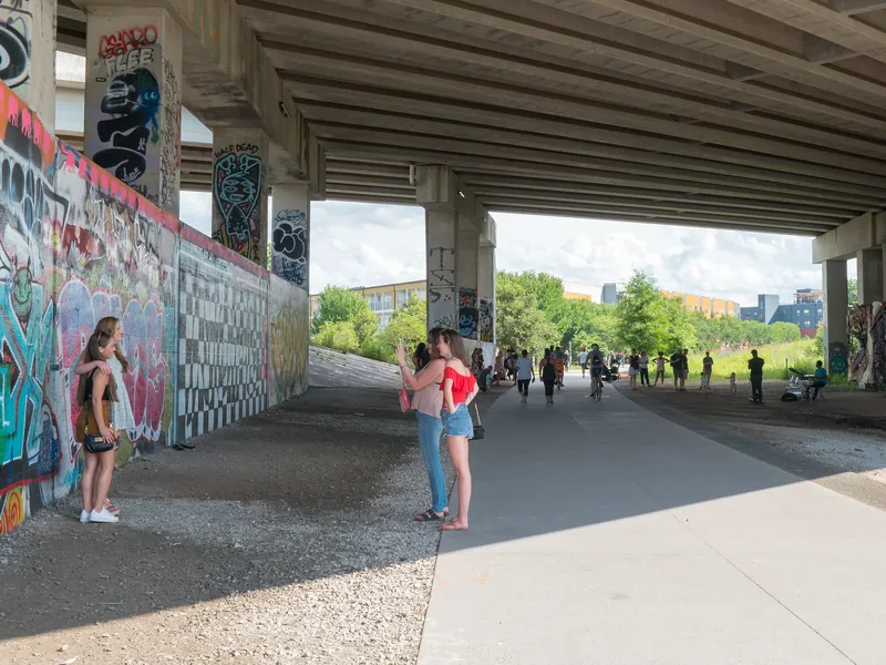 People walking past murals in the gathering space under Freedom Parkway on the BeltLine Eastside Trail