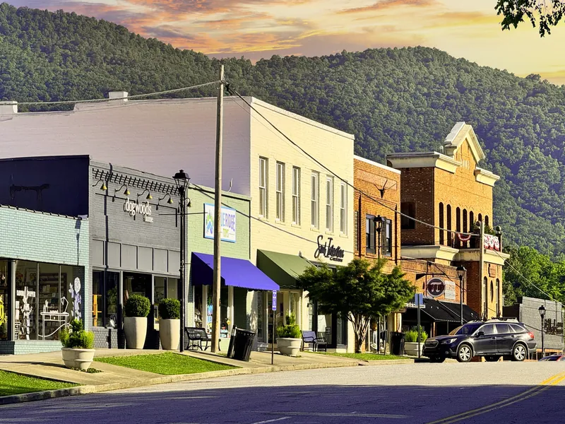 Downtown Clayton storefronts with green mountains rising behind