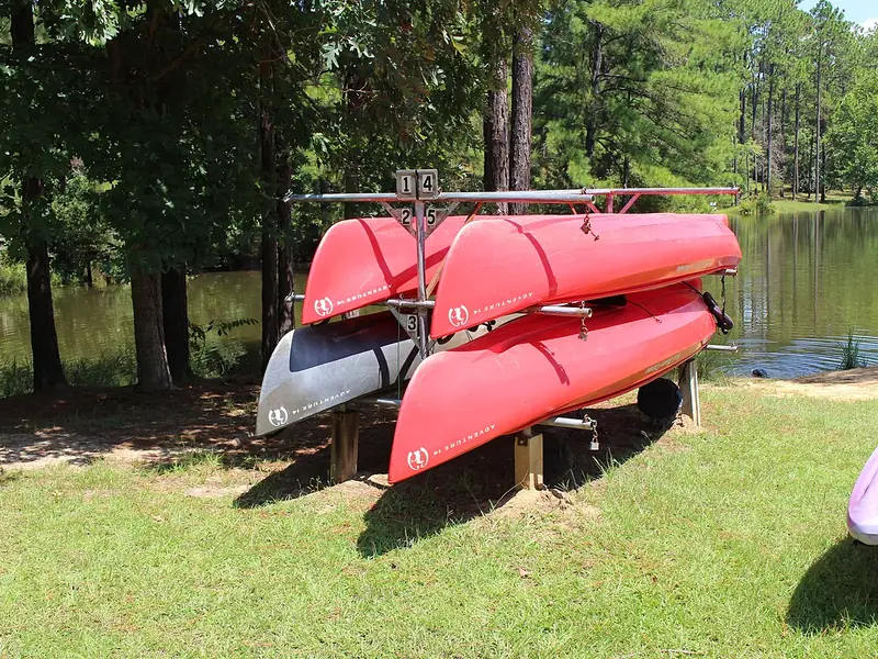Red canoes stacked beside the lake at General Coffee State Park