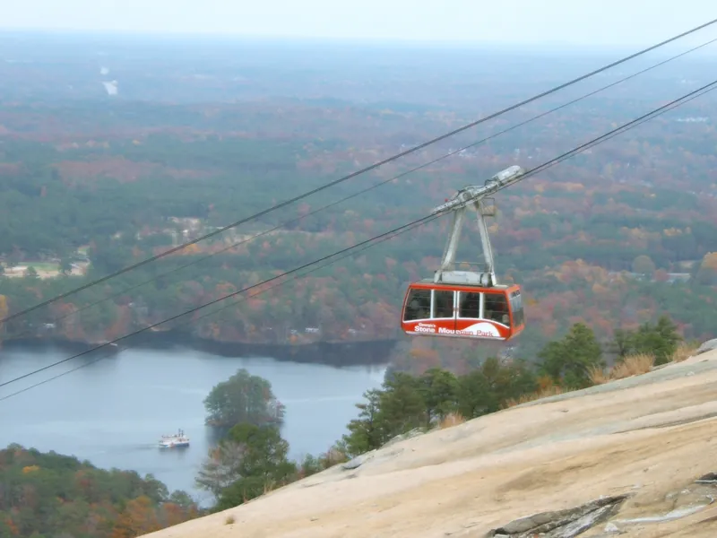 The red Summit Skyride cable car climbing Stone Mountain above the lake