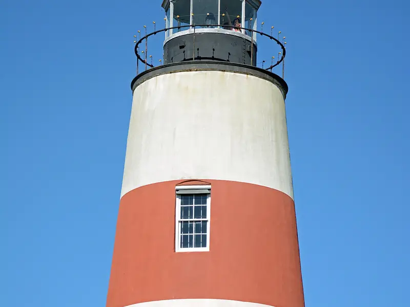 Red-and-white striped Sapelo Island Lighthouse against a blue sky