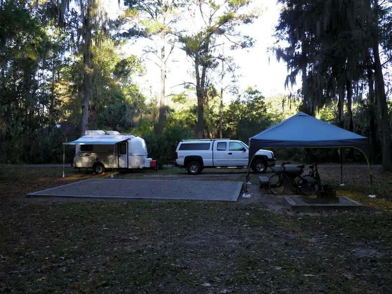 Campsite with a camper and canopy under the trees at Skidaway Island State Park