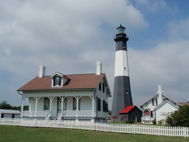 The black and white Tybee Island Lighthouse beside the historic keeper&rsquo;s cottage