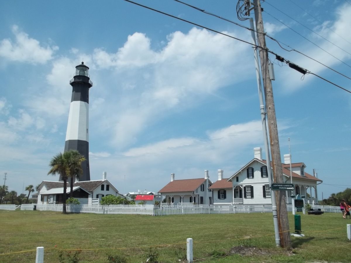 The black and white Tybee Island Lighthouse and its historic keeper&rsquo;s cottages