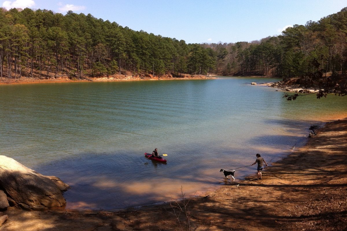 A kayaker and a hiker with a dog at the edge of Lake Allatoona at Red Top Mountain State Park