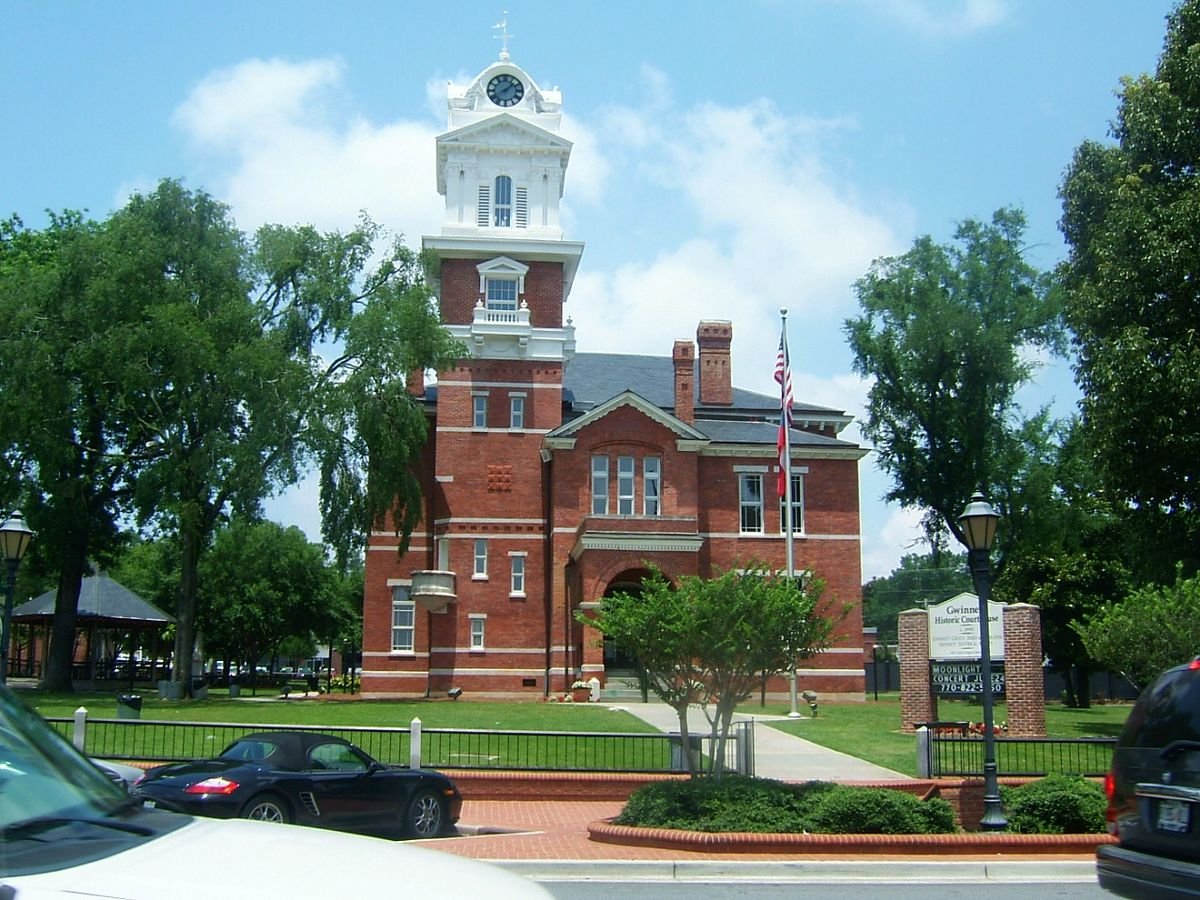 The red brick Gwinnett Historic Courthouse and its white clock tower on the square in Lawrenceville