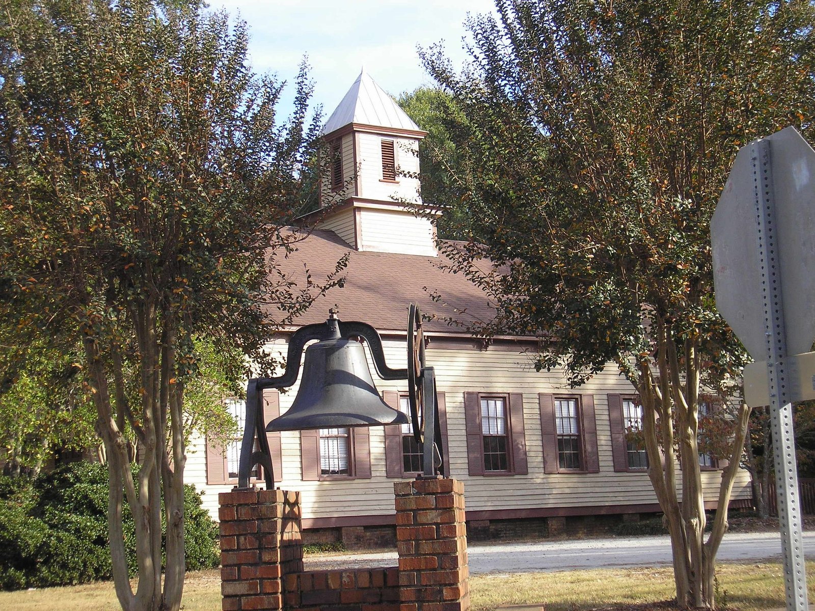 The white frame Male Academy building with a cupola, and a school bell on a brick base, at College Street and Temple Avenue in Newnan