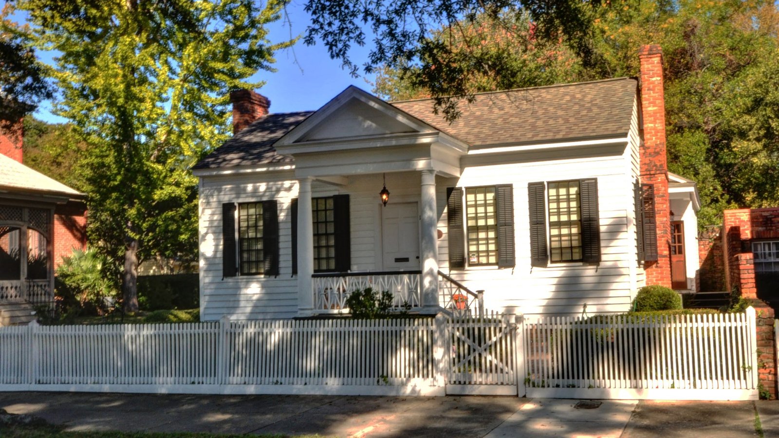 The white Pemberton House cottage with a small columned porch and picket fence in Columbus