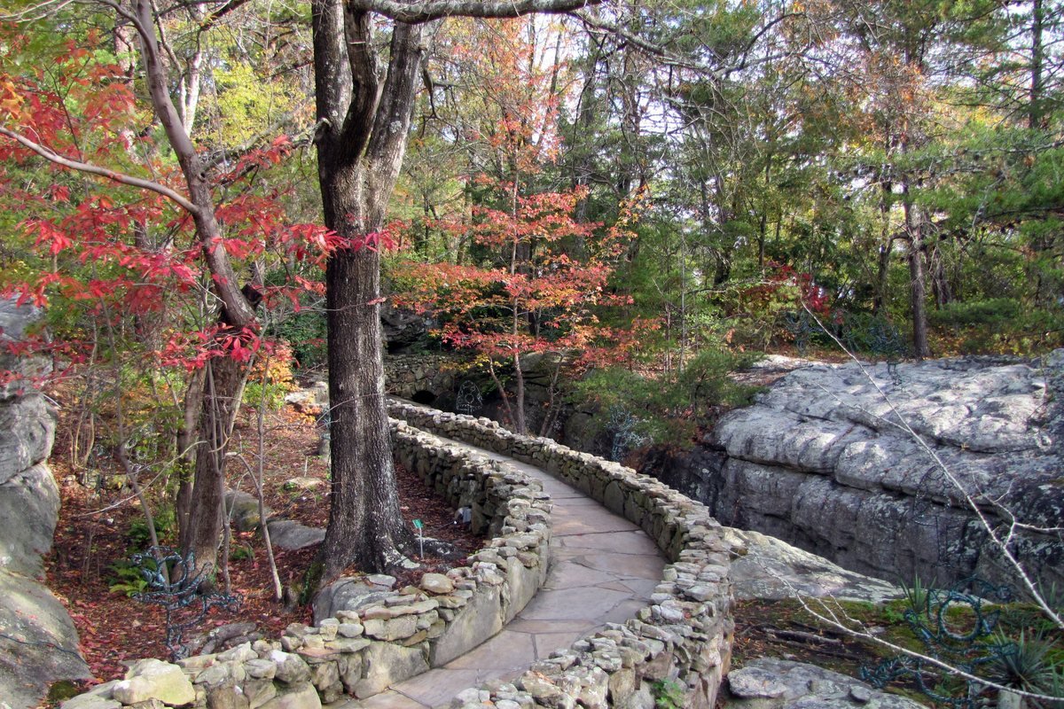 A stone path curving between sandstone boulders and fall color at Rock City Gardens on Lookout Mountain