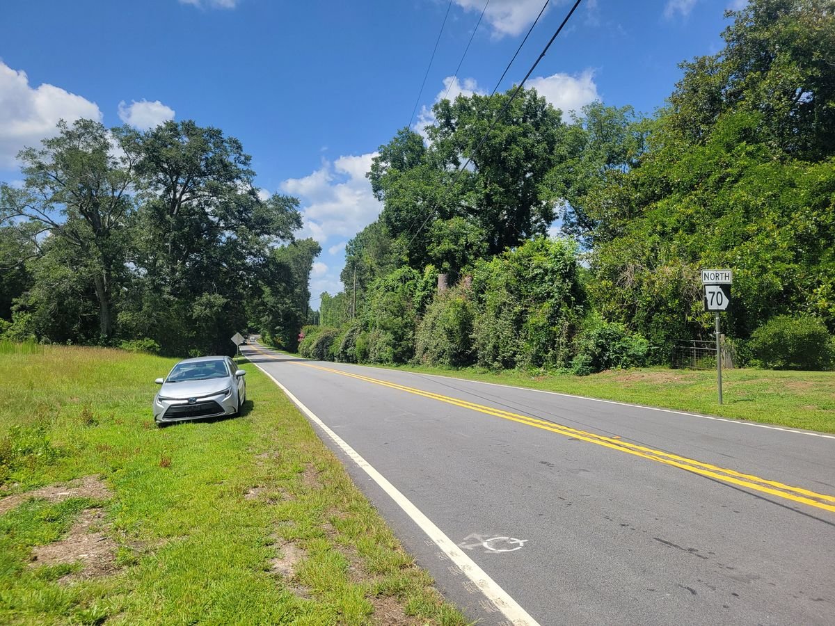 Two-lane State Route 70 curving through green woods in Chattahoochee Hills on the South Fulton Scenic Byway